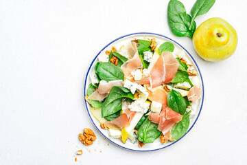 Pear salad with prosciutto, blue cheese, spinach, walnuts on white background, top view, copy space