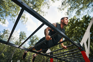 Motivated handsome male doing powerful training outdoors