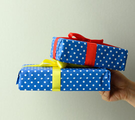 female hand holding a stack of gift boxes tied with silk ribbon on a gray background, surprise and win
