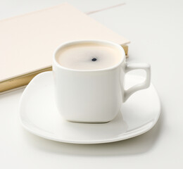 white ceramic cup with black coffee stands on a white table, top view, breakfast