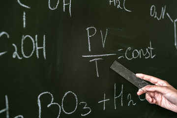 female teacher explane chemical formulas near chalkboard