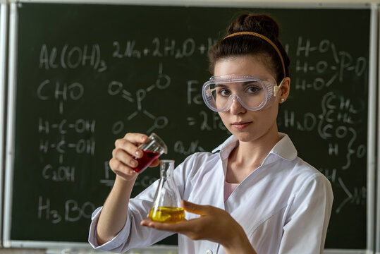 Student in white coat doing experiment test in chemistry laboratory with liquid formula