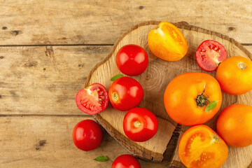Assorted ripe tomatoes on a wooden stand. Fresh red and orange organic vegetables