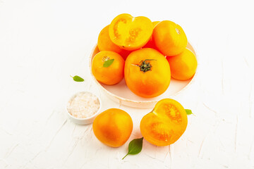 Ripe orange tomatoes with fresh basil. New harvest vegetables on a ceramic stand