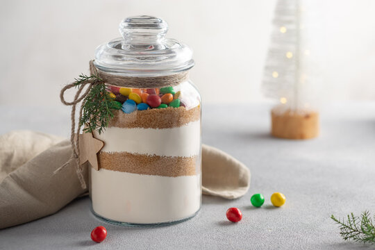 Cookies mix with color candies in glass jar. Dry ingredients for making Christmas cookies. xmas sweet, winter holidays concept.