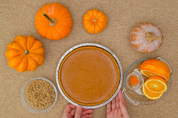 Fresh baked homemade pumpkin pie decorated with crushed nuts and orange zest. Ingredients close up on rustic background