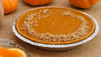 Fresh baked pumpkin pie close up in disposable baking pan, just from the oven. Decorating pie with crashed nuts. Homemade dessert
