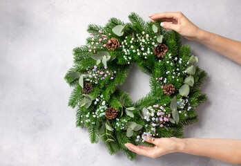 florist hands holding Christmas wreath with flowers, eucalyptus and cones. Christmas wreath...
