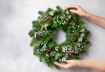florist hands holding Christmas wreath with flowers, eucalyptus and cones. Christmas wreath workshop. top view. space for text © Mila Naumova