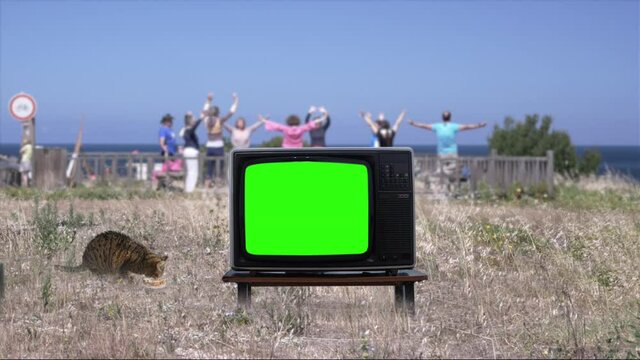 Old TV Green Screen People Practicing Yoga On Background, Retro Television. Vintage Television Green Screen In Front Of Many Senior People Practicing Yoga In Nature