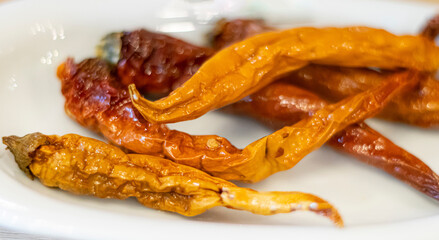 Dried and crispy capsicum. Hot red peppers served on a plate.
