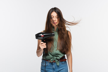 young woman with shiny hair using hair dryer isolated on grey