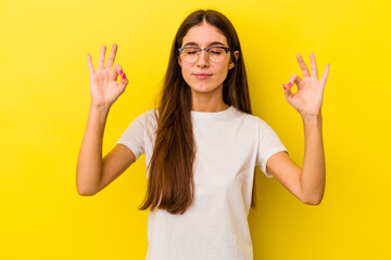 Young caucasian woman isolated on yellow background relaxes after hard working day, she is performing yoga.