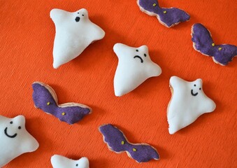 Halloween cookies in the shape of a ghost and a bat on an orange background