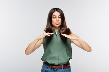 young woman looking at hair ends isolated on grey