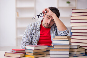 Young male student and too many books in the classroom