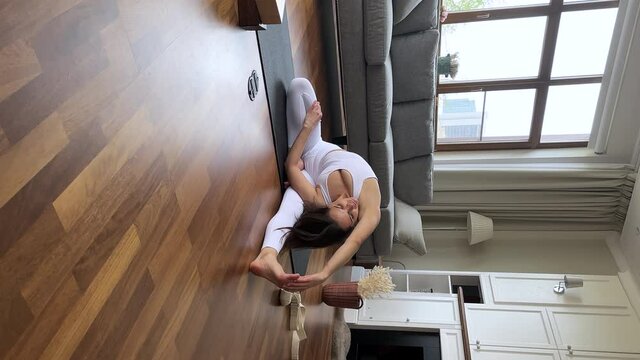 Vertical view young pretty woman in activewear sit on mat doing Revolved Head-to-Knee Parivrtta Janu Sirsasana pose, stretches body active exercise. Yoga asanas for mental and physical health concept