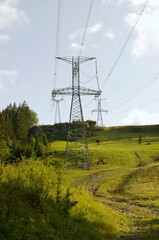 High voltage eletrical towers and lines with blue sky and green meadow. Eletricity towers on a...