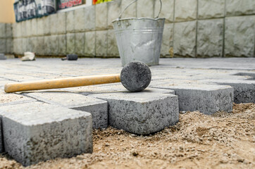 Rubber hammer on a gray pavement on the sand. Laying paving stones in the city.