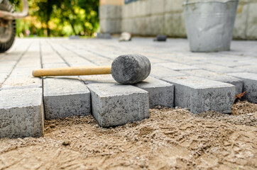 Hammer for sealing the pavement on the newly laid pavement. The process of laying paving stones.