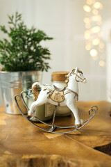 A vintage toy of a white rocking horse and a new year tree stands on a wooden table. New Year and Christmas interior decoration 