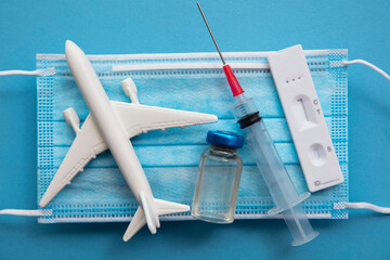Covid air travel background. Airplane with a coronavirus protective face mask vaccine needle and test.