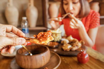 Man and woman eating delicious grilled tabaka chickens with tkemali sauce in a traditional Georgian cuisine restaurant
