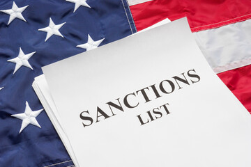 USA flag and sanctions list pile of papers on it.