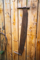 an old two-handed saw is hanging on a wooden wall