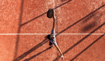 View from above of a man who is playing paddle tennis and has just hit the ball.