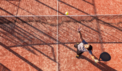Top view of a paddle tennis player hitting the ball near the net on a court. © REC Stock Footage