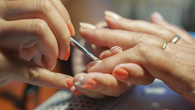 Manicure procedure. Applying nail polish in nail salons. Concept of beauty treatment, femininity, fashion and beauty products.