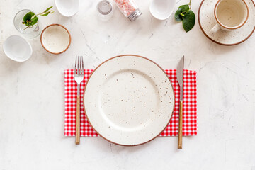 Tableware set with empty plate with dishware and glasses on napkin