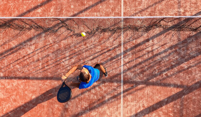 View from above of a professional paddle tennis player hitting the ball near net