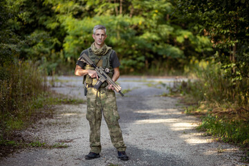 A man standing with an airsoft assault rifle in military uniform