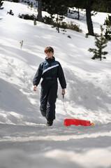 chica joven caminando con un trineo en mano sobre la nieve fría de invierno