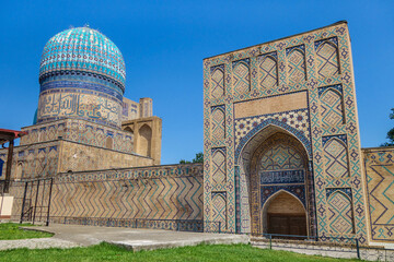 Western part of Bibi-Khanym mosque complex in Samarkand, Uzbekistan. Portal and dome of mosque decorated with oriental patterns are visible