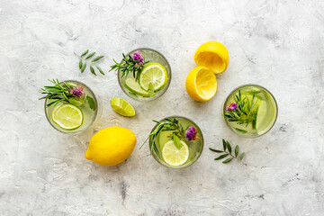 A lot of glasses of lemonade with summer herbs and lemon slices