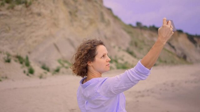 Selfie woman taking picture on travel holiday in vacation destination. Curly woman holding mobile photo to take self-portrait photo.