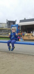 A todler boy eats ice cream sitting on a bench outside. Parks and recreation areas of citizens.