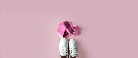 Top view of female sneakers and  booty bands on pink background. Intensive gluten workout cocnept.Large image for web banner with copy space