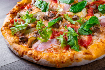 Pizza with cheese, Bolognese sauce, minced meat, bacon, tomato and vegetables. Italian pizza on wooden background.