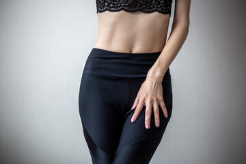 Woman slim figure in a black lingerie, close-up photo on a simple background. Fitness and sport model