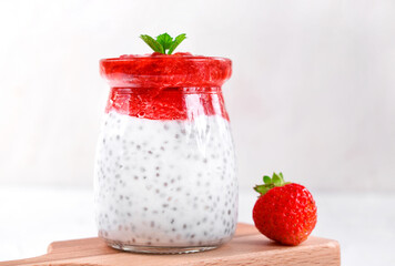 Chia pudding with coconut milk and strawberry puree served in the glass jar. Healthy layered dessert. Vegan food