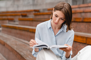 Young student woman freelacer reading book preparing for educational exam at college university...