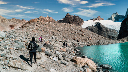 People trekking through the mountains. with their sticks they walk on the rocks.