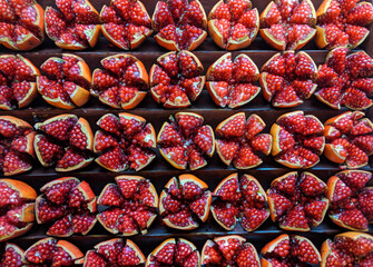 A group of many pomegranate fruit cut in pieces divided equally in sections forming background.