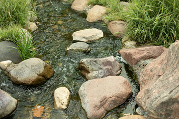 Naklejka na ściany i meble Water runs over the stones. Fresh water stream.