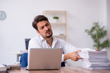 Young male employee and too much work in the office