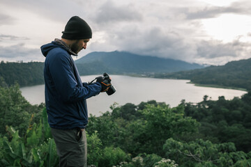 A man, a traveler, with a backpack, photographs a wild landscape.